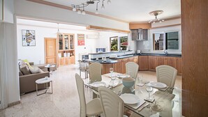 A spacious kitchen with modern appliances, a dining area with a glass table, and a cozy living room with a sofa and chairs. - Luxury 5BDR Villa with Private pool, and wheelchair accessible flat (Paralimni)