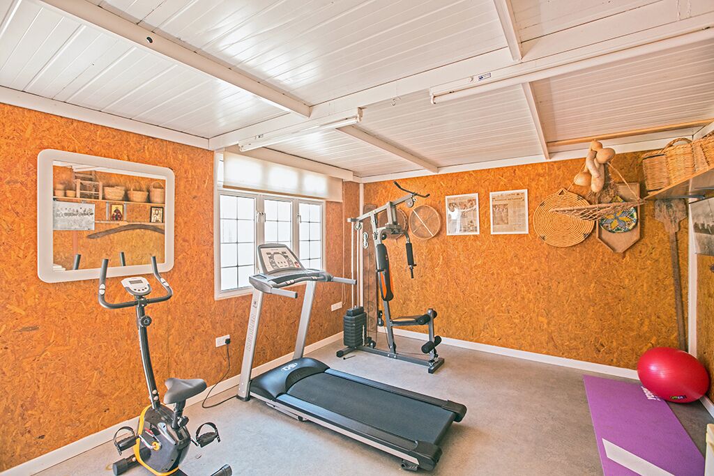 A gym with exercise equipment, a treadmill, and a wall-mounted rack with baskets.