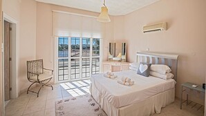 A bedroom with a bed, a chair, a bedside table, a mirror, and a window with a view. - Luxury 5BDR Villa with Private pool, and wheelchair accessible flat (Paralimni)