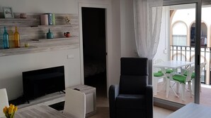 A modern living room with a dining area, a black armchair, and a TV. - Perfectly located, refurbished apartment in a gated complex with pool and garden (Torrevieja)
