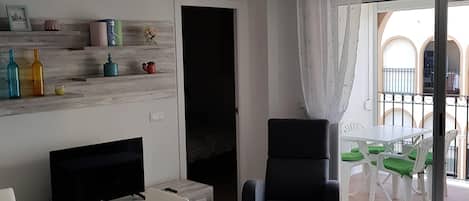 A modern living room with a dining area, a black armchair, and a TV.