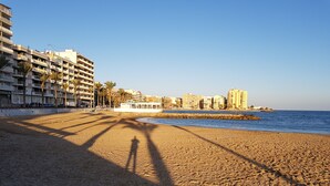 A sandy beach with a row of multi-story buildings in the background. - Perfectly located, refurbished apartment in a gated complex with pool and garden (Torrevieja)