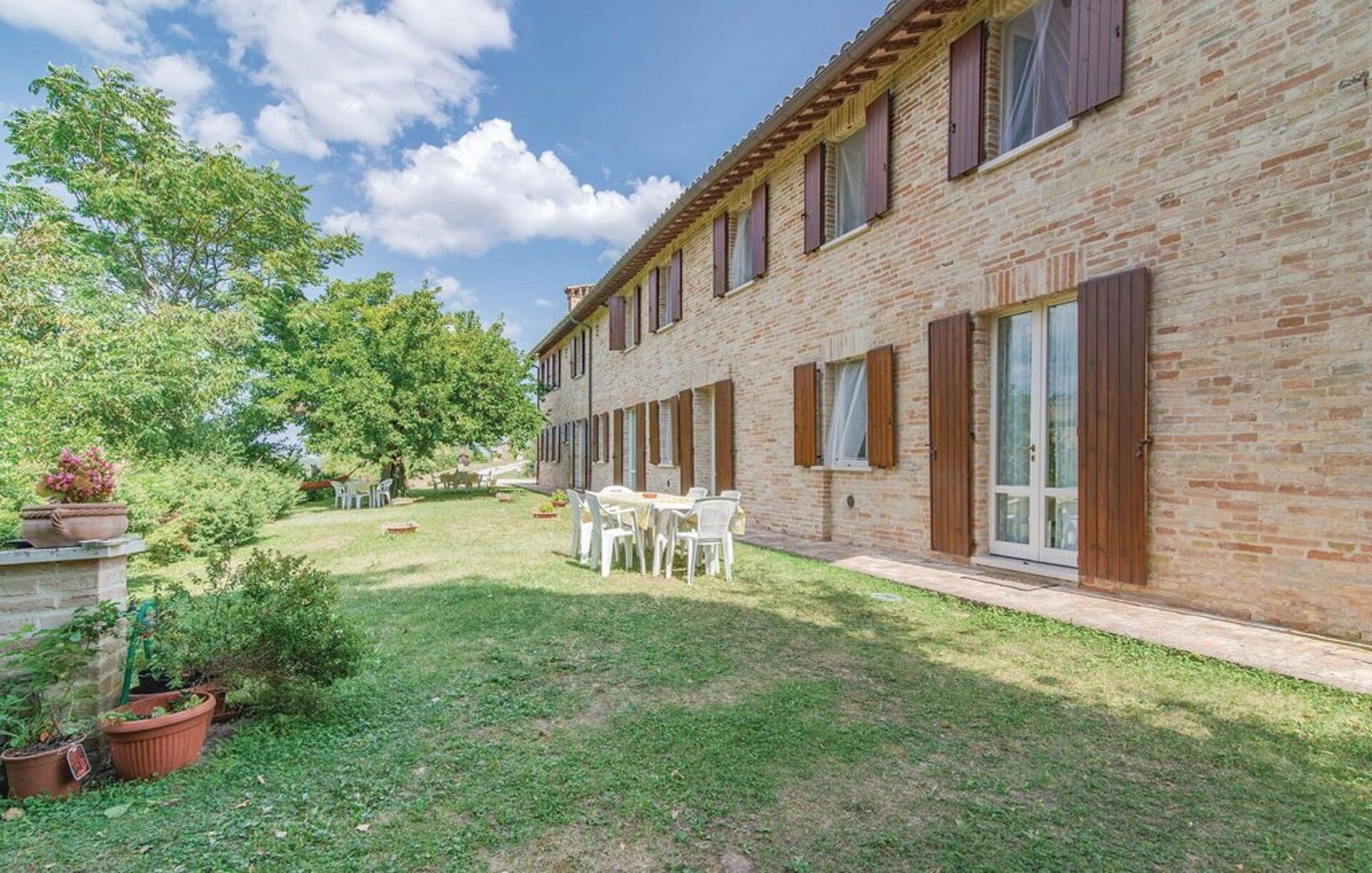 Un bâtiment en briques doté d’un patio avec jardin, d’un espace extérieur aménagé pour s’asseoir et de plantes en pot.