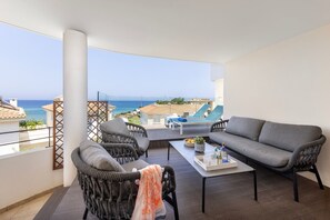 A balcony with a grey sofa, wicker chairs, and a table with a tray.