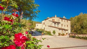 Un edificio in pietra con vialetto sterrato e recinzione in legno.