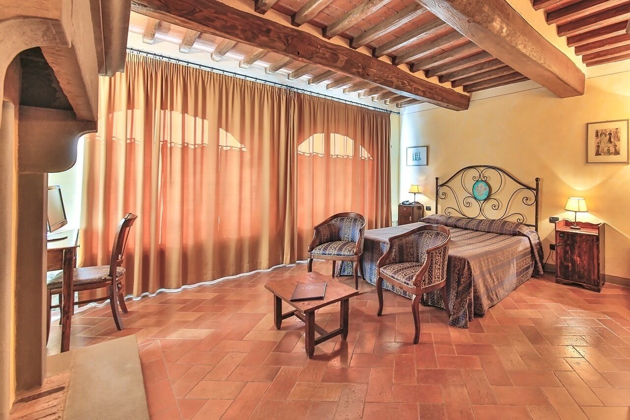 Une chambre à coucher comprenant un lit, deux chaises, une petite table et un bureau avec une chaise.