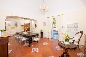 A spacious room with a dining table, chairs, a sofa, a coffee table, and a view of a pool.