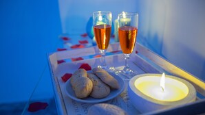A tray with two glasses of amber liquid, a lit candle, and a plate of cookies on a table with a blue background. - Versomare - Room Grecale - extra Bed On Demand (Polignano A Mare)