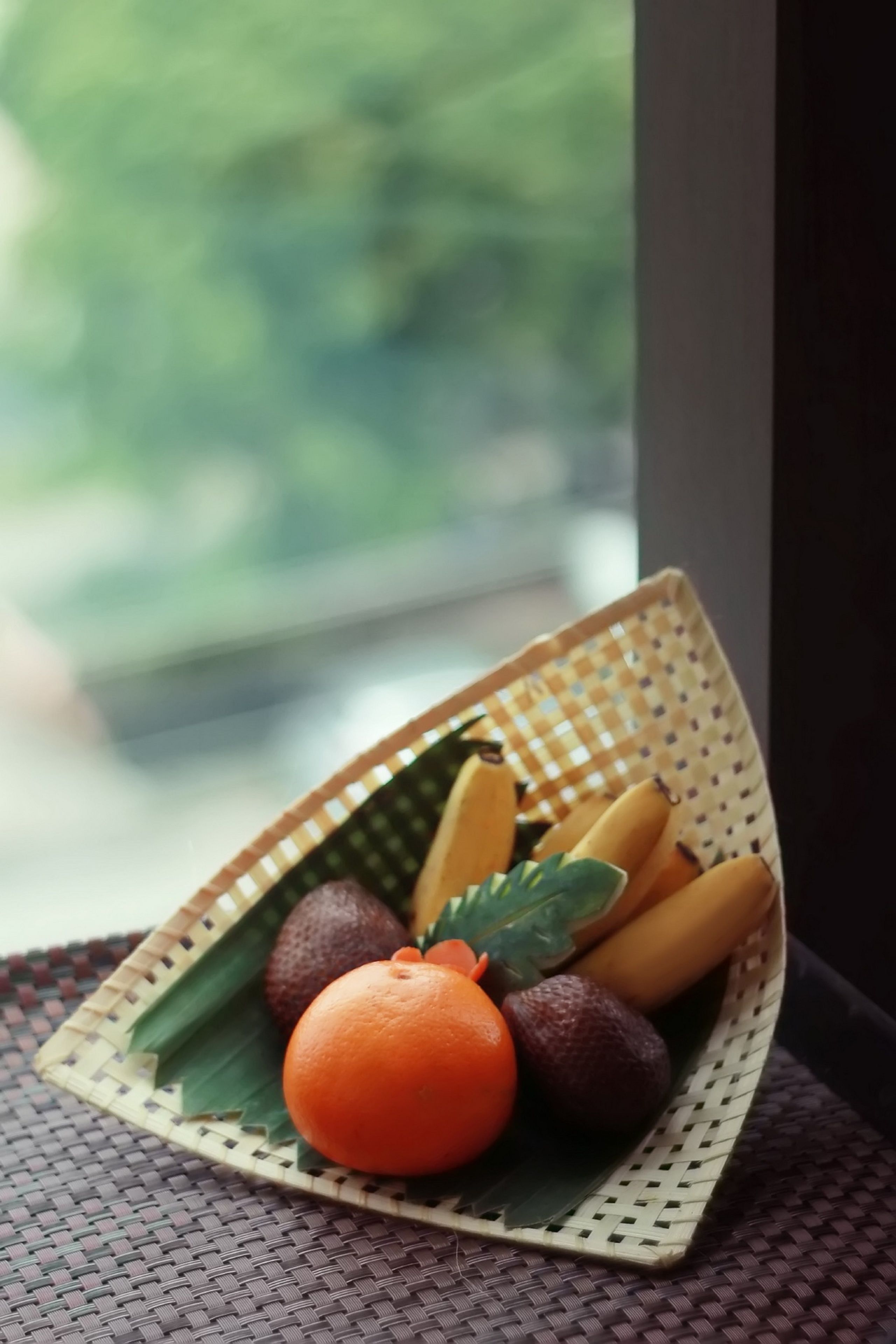 A woven basket containing fruits on a woven mat.