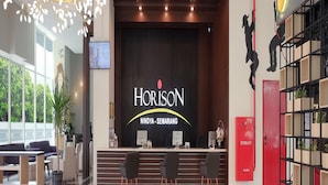 A modern hotel lobby with a reception desk, seating area, and a large chandelier. - Hotel Horison Nindya Semarang (Semarang)