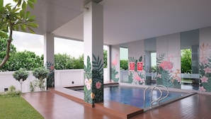 An indoor swimming pool area with wooden flooring, a pool with a metal ladder, and walls decorated with floral murals. - Hotel Horison Nindya Semarang (Semarang)
