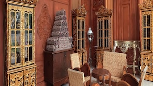 A room with ornate wooden paneling, a large cabinet with glass doors, a decorative stack of items, and a patterned rug. - Hotel Horison Nindya Semarang (Semarang)