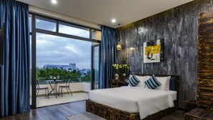 Un dormitorio moderno con una cama grande, un balcón con mesa y sillas, y vistas a la ciudad.