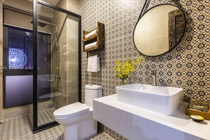 A modern bathroom with a glass-enclosed shower, a white toilet, a large sink, and a mirror. - Caprice Hotel Danang (Da Nang)