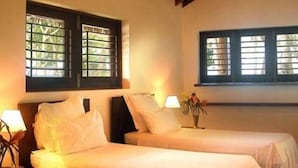 A room with two beds, wooden beams on the ceiling, and windows with blinds. - Vanuatu Uncharted Sport Fishing Lounge (Mele)