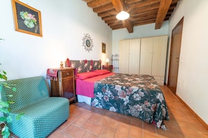 A bedroom with a bed, a chair, a wardrobe, and a wall decoration.