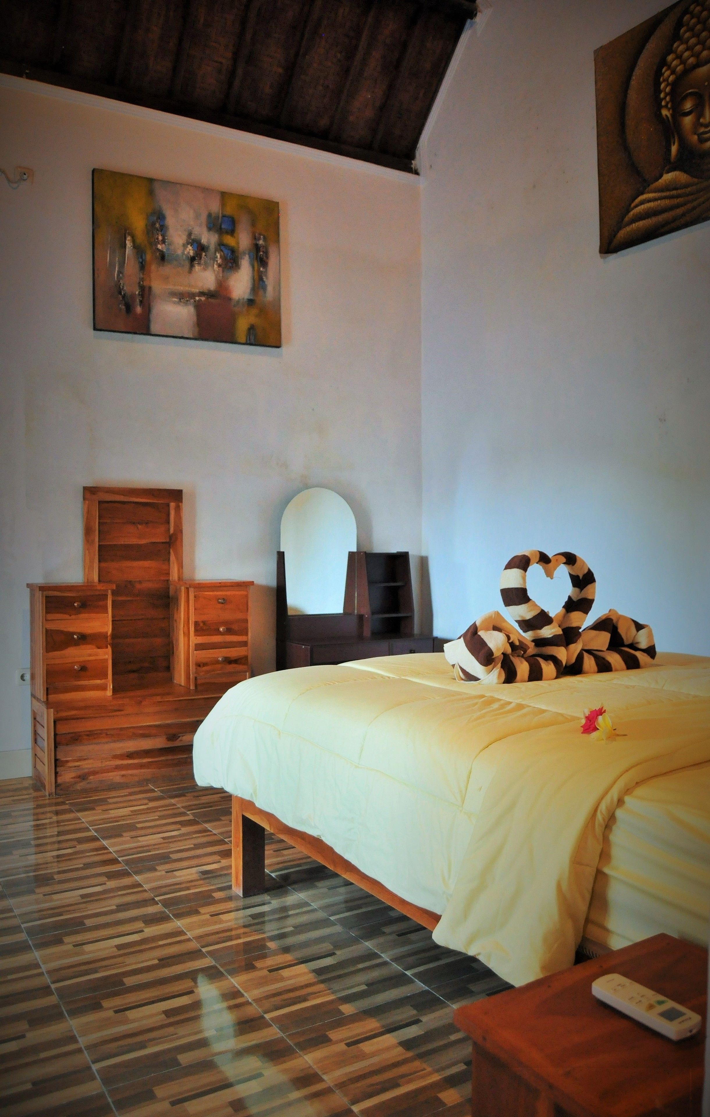 Quarto com cama, cómoda de madeira e um quadro na parede.