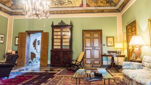 A room with a chandelier, a wooden cabinet, a chair, a sofa, and a table with a lamp. - Charming nineteenth-century villa in Caltagirone (Caltagirone)