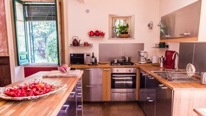 A modern kitchen with stainless steel appliances, wooden countertops, and a window with a view of greenery. - Charming nineteenth-century villa in Caltagirone (Caltagirone)