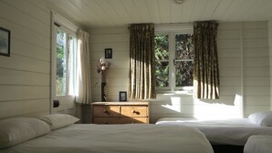 A bedroom with two beds, a wooden dresser, and a window with curtains. - Amazing New Forest location - Sleeps up to 14 people (Brockenhurst)
