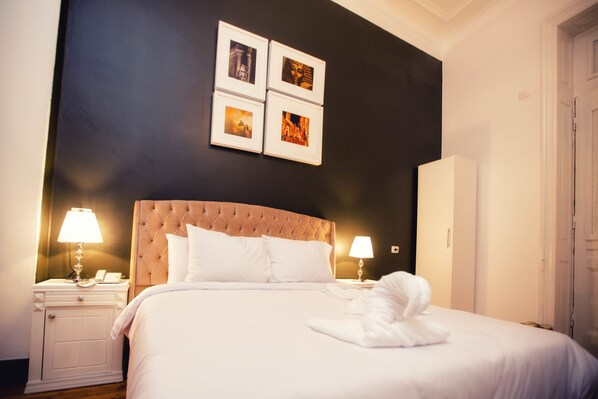 A hotel room with a large bed, two bedside lamps, a nightstand, and a wall with four framed pictures. - The Square Boutique Hotel (Cairo)