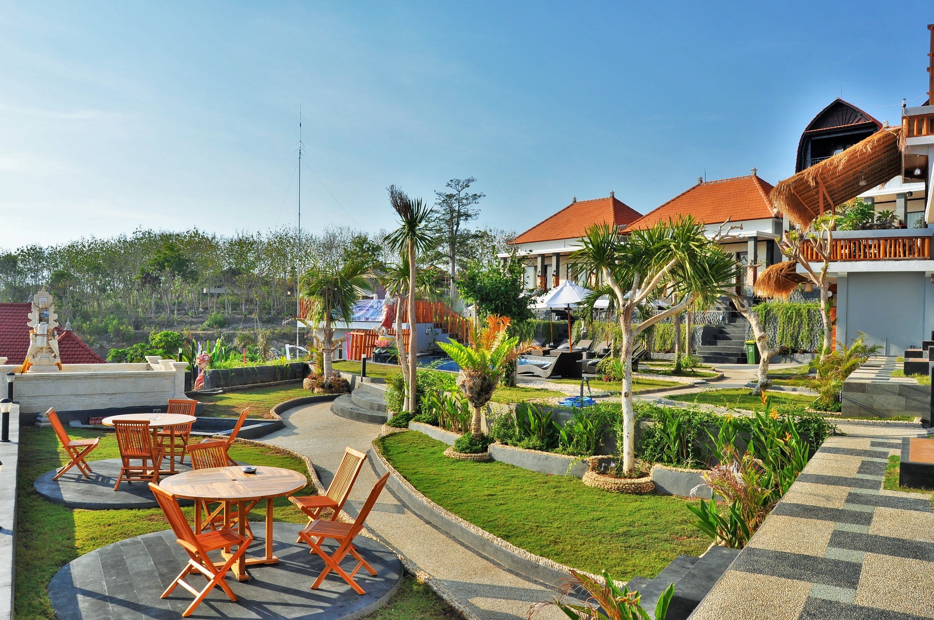 A resort with outdoor seating, palm trees, and a pool area.