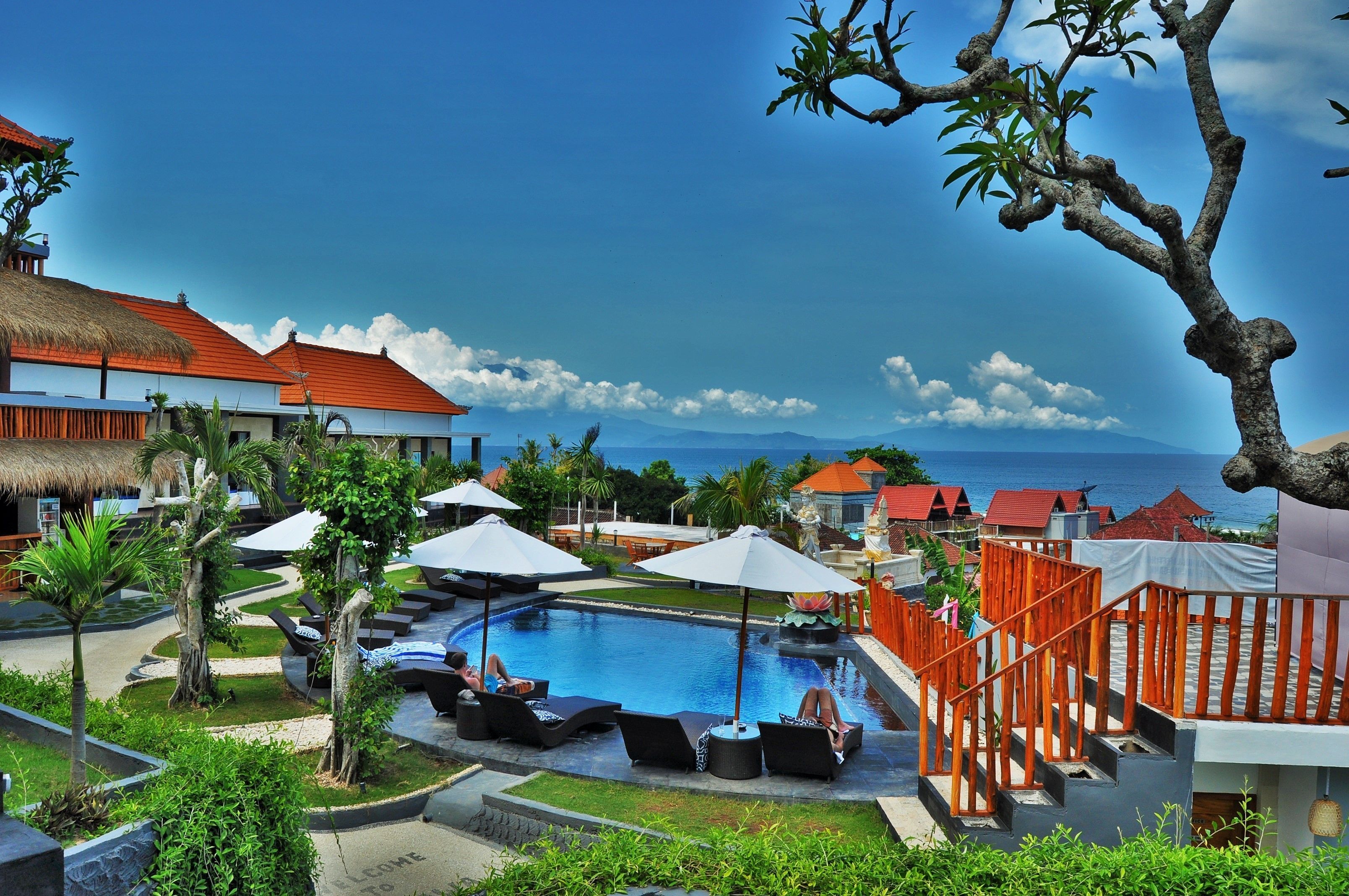 A resort with a swimming pool, lounge chairs, and a view of the ocean.
