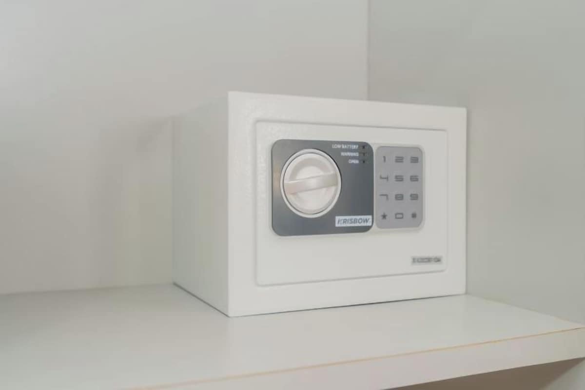 A white, modern, wall-mounted safe with a digital keypad and a large dial lock.