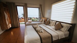 A hotel room with a large bed, a wooden floor, a view of the sea, and a balcony with a wooden railing. - Pandawa Beach Resort and Spa Luxury (Penida Island)