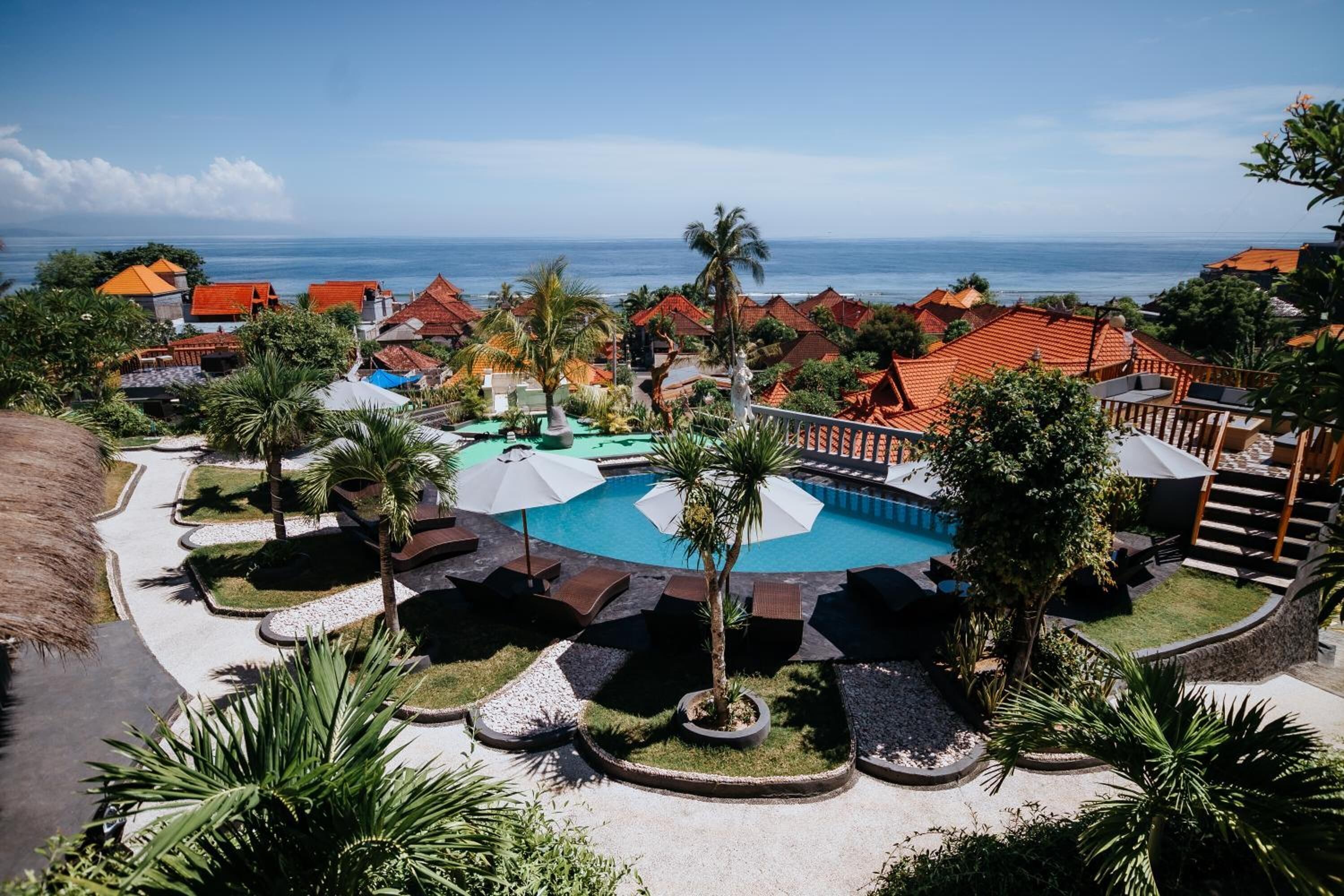 A resort with a swimming pool, palm trees, and ocean views.