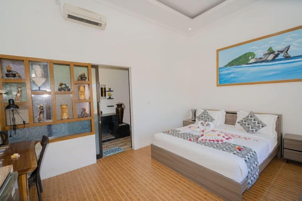 A bedroom with a bed, a desk, and a shelf with decorative items.