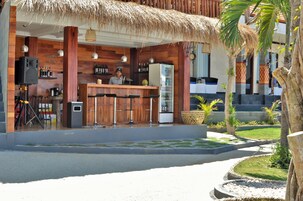 Un restaurante con fachada de madera, zona de bar y techo de paja.