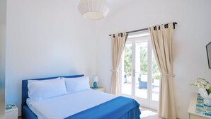 Une chambre à coucher avec un lit, des rideaux, une lampe et une vue sur l’extérieur.
