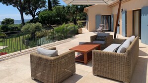 A patio with wicker furniture, a wooden table, and an umbrella. - Luxury, modern villa, 8min walking distance to town and beaches - heated pool (Sainte-Maxime)