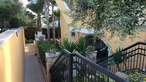 Uma escadaria de pedra com corrimão de metal que leva a um edifício com fachada amarela.