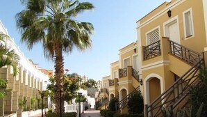 A paved walkway flanked by palm trees and buildings with balconies and staircases. - El Veril Duque, 2 bed apartment, sleeps 4, only 7 min walk to El Duque beach (Costa Adeje)