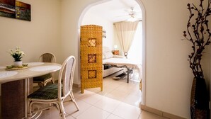 A room with a bed, a dining table with chairs, a decorative pillar, and a view through an archway to another room. - El Veril Duque, 2 bed apartment, sleeps 4, only 7 min walk to El Duque beach (Costa Adeje)