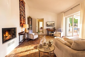 A cozy living room with a fireplace, comfortable seating, and a view of the outdoors. - Cozy family-friendly holiday home with many extras (Sao Bras de Alportel)