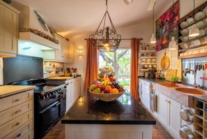 A kitchen with a central island, a stove, cabinets, and a hanging light fixture.