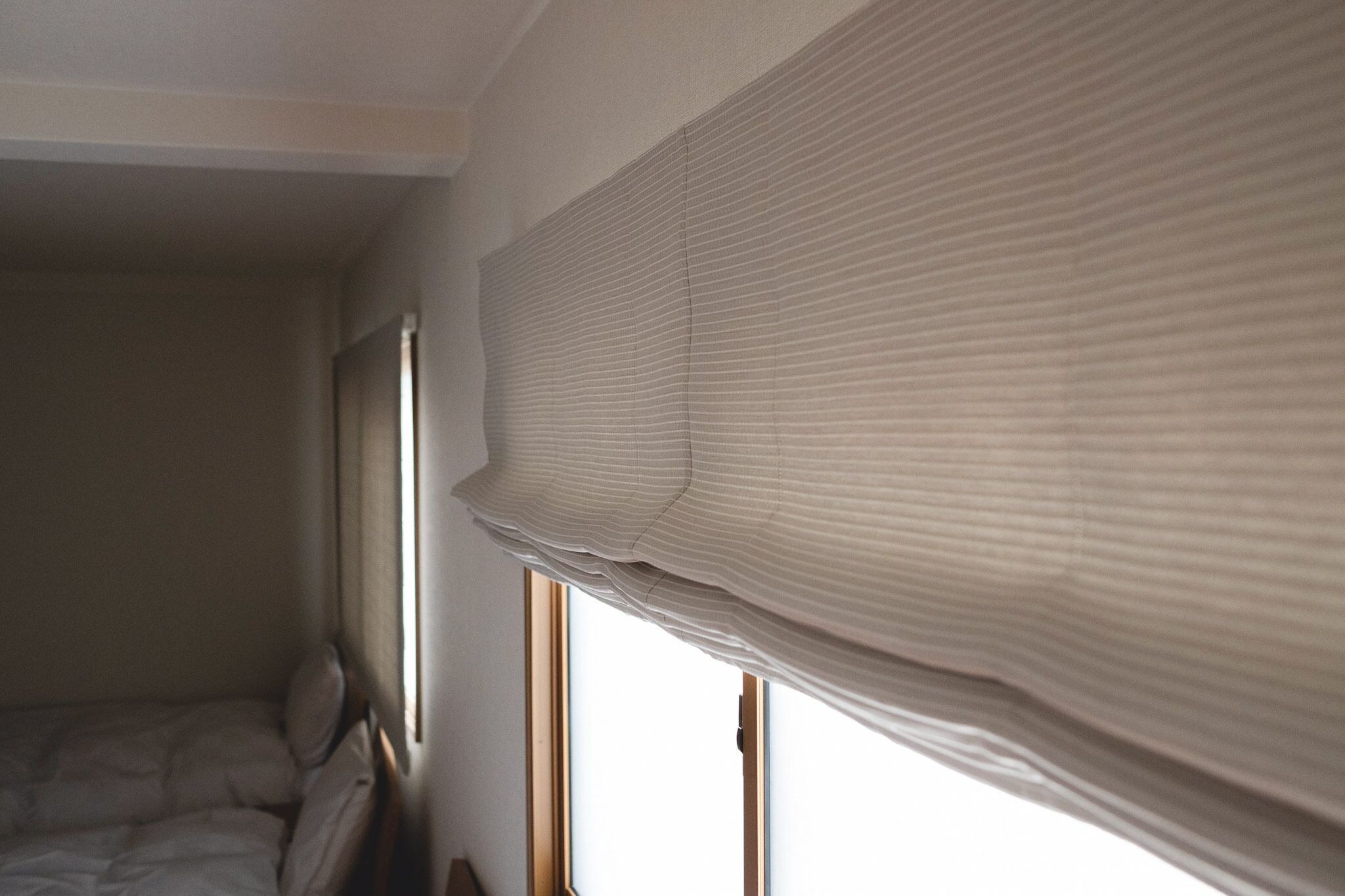 A bedroom with a bed, a window, and a partially drawn curtain.