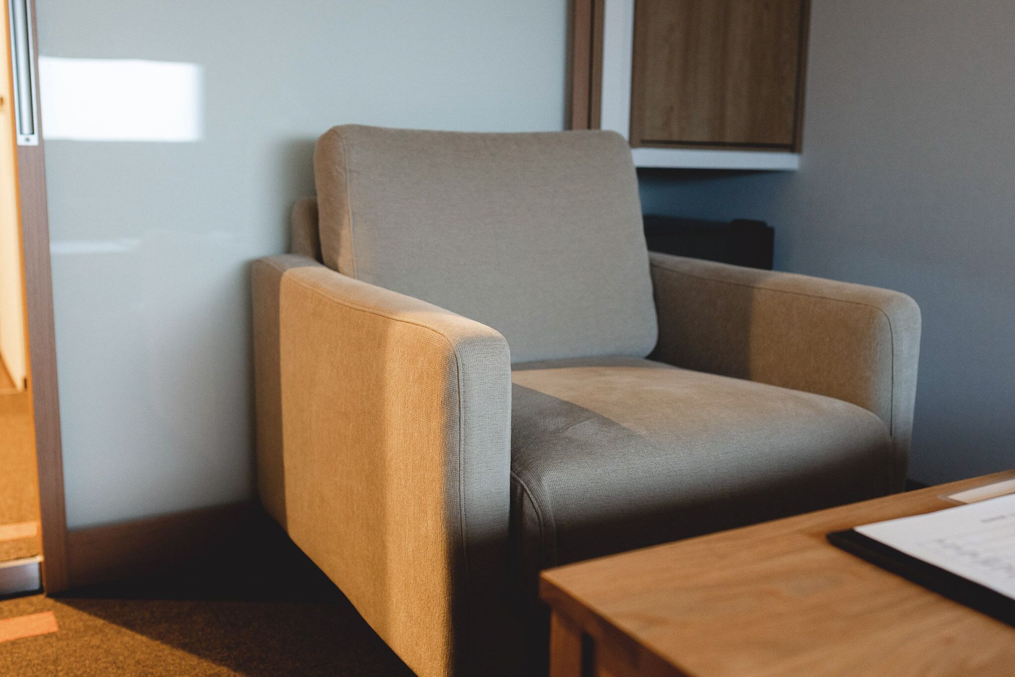 Un coin de pièce avec un fauteuil beige et une table en bois.