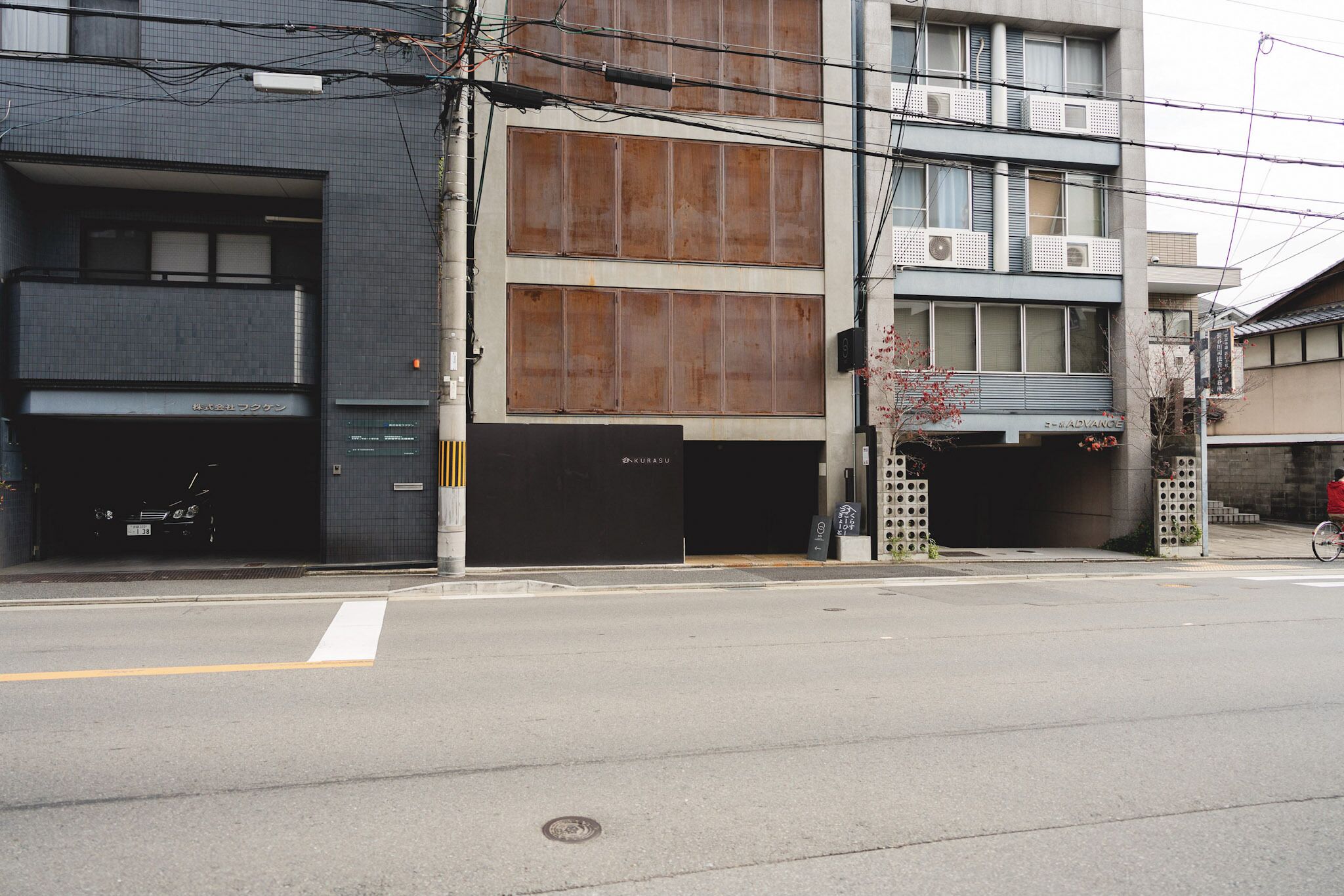 A building with multiple garage doors, a clear road in front, and visible electrical wires overhead.