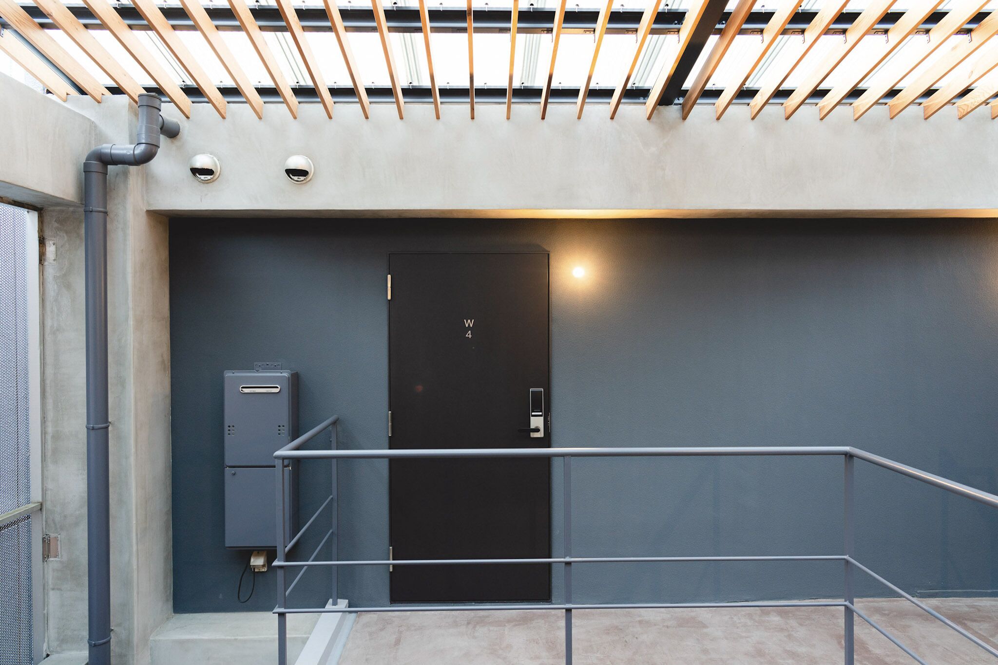Un ascensor moderno con puerta negra, barandales de metal y pared de concreto.