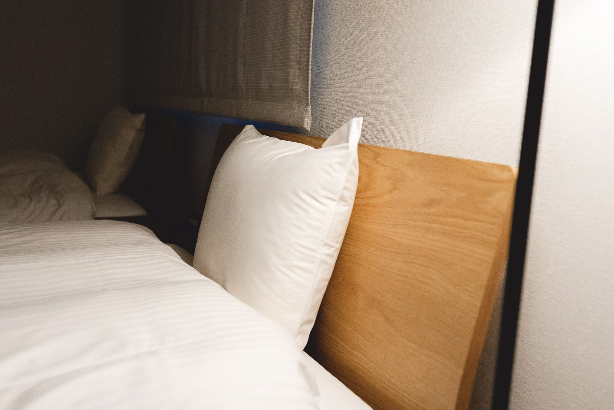 Una cama bien hecha con ropa de cama blanca y un cabecero de madera.
