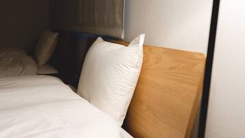 A neatly made bed with white bedding and a wooden headboard.
