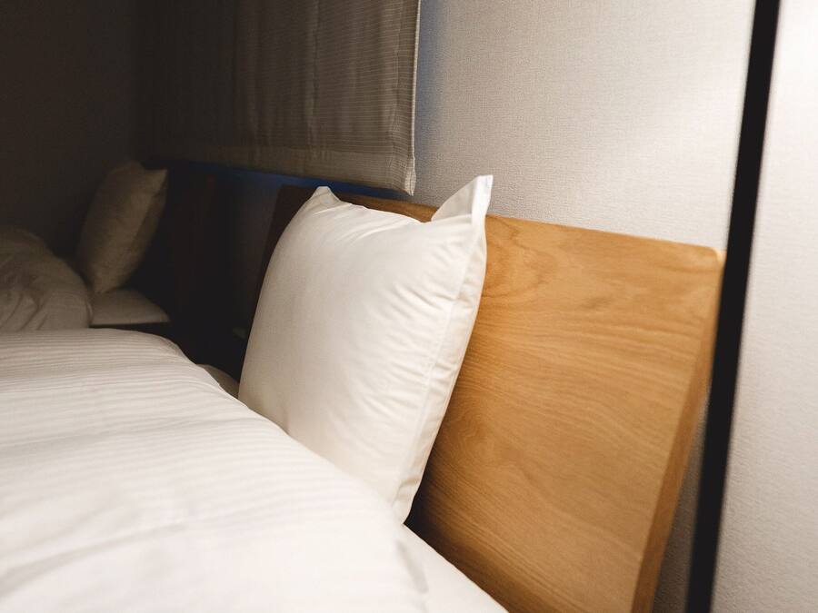 A neatly made bed with white bedding and a wooden headboard.