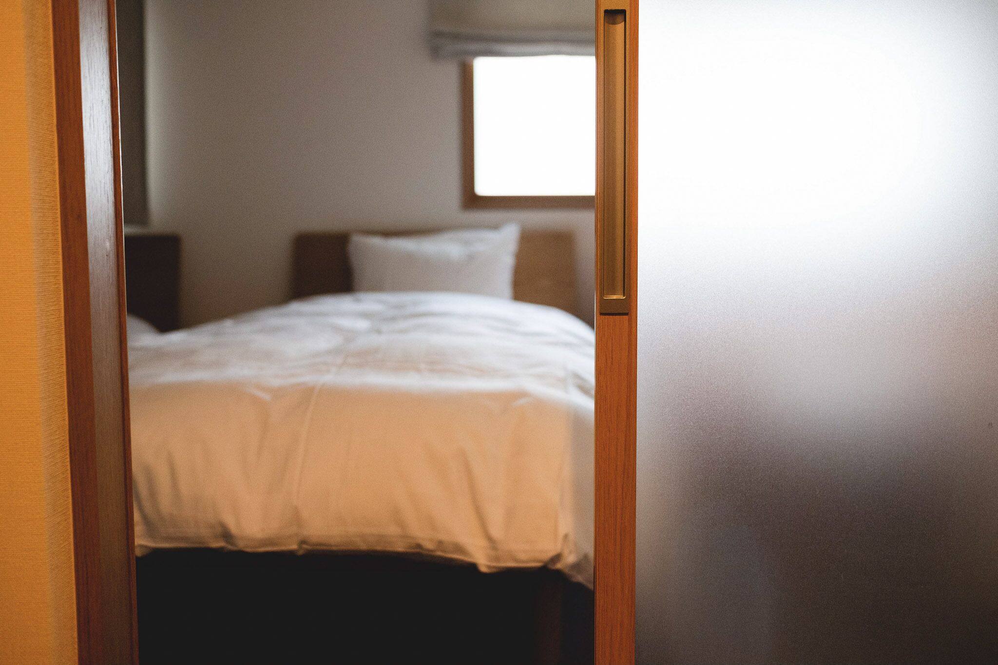 A bedroom with a bed, a window, and a door frame.