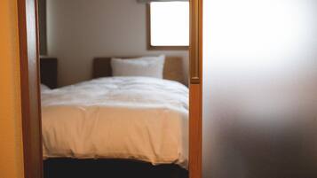 A bedroom with a bed, a window, and a door frame.