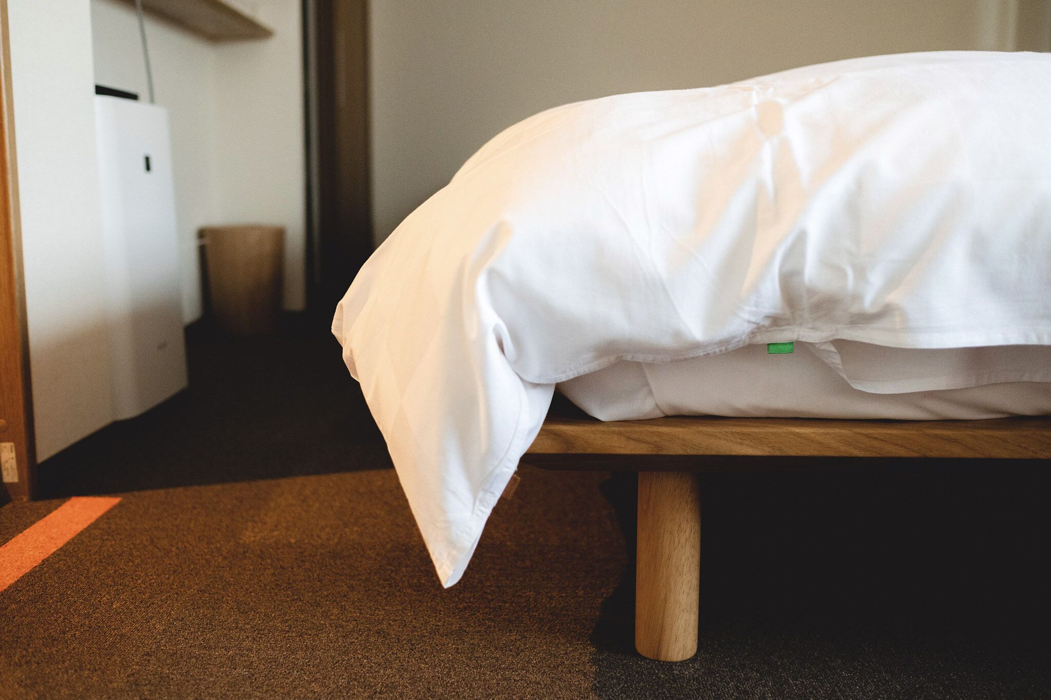 A neatly made bed with white bedding in a hotel room.