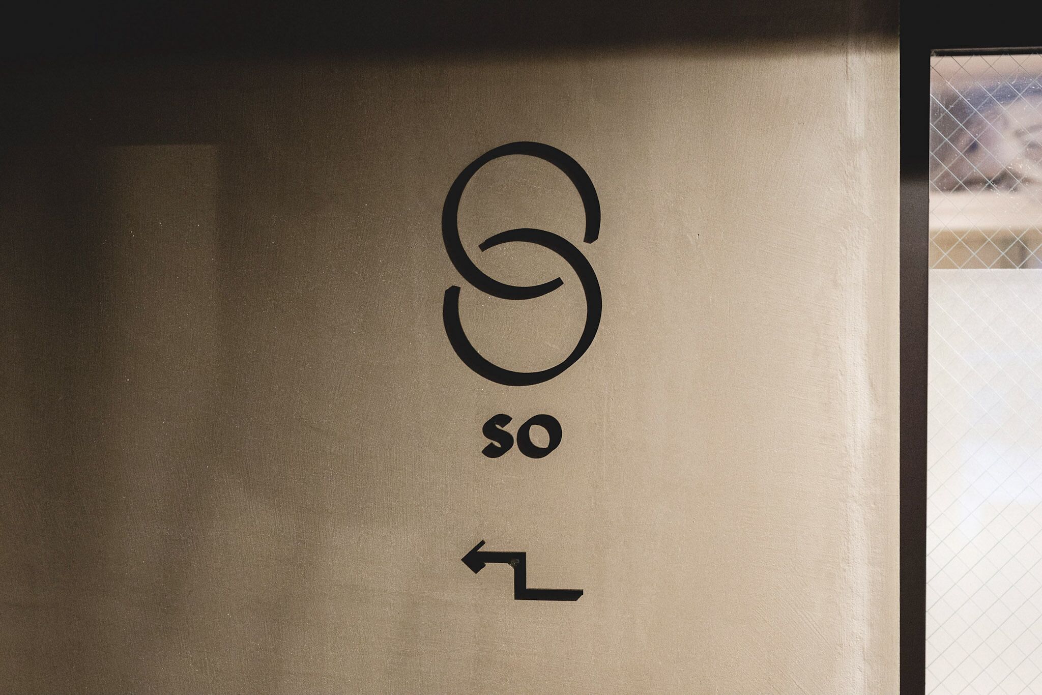 A sign with a logo and text, and an arrow pointing left.